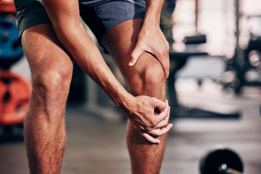 Fitness, exercise and man with knee pain in gym holding leg after injury, accident and muscle pain