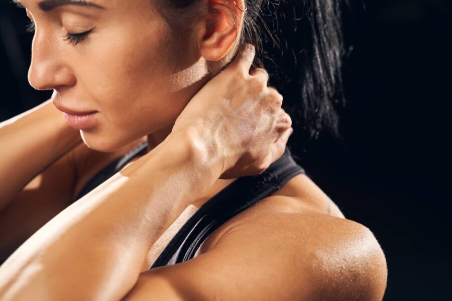 Cropped photo of a beautigul sportswoman having her eyes closed and touching her neck at the gym
