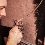 A man fixes a burnt socket. Short circuit, burnt wires. traces of smoke and fire on the wall. The electrical outlet was completely burnt and melted, the voltage drop from the use of an electric heater